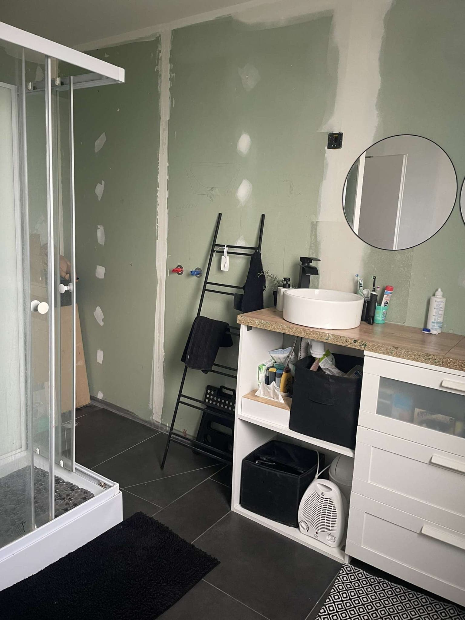 La cabine de douche d'origine, carrelage sombre et murs bruts